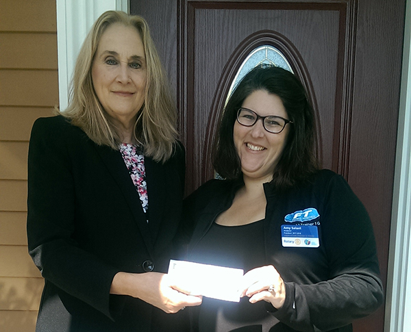 Agent Patricia Curley presents Rotary President Amy Salant with a donation